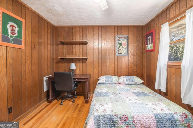 bedroom with wooden walls and light hardwood / wood-style flooring