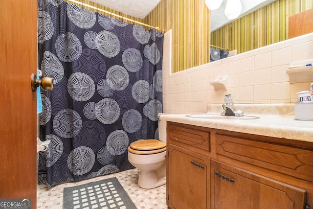 bathroom with vanity, tile walls, and toilet