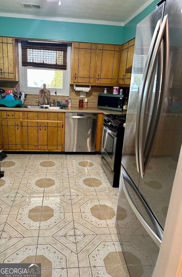 kitchen with sink, appliances with stainless steel finishes, tasteful backsplash, ornamental molding, and light tile patterned flooring