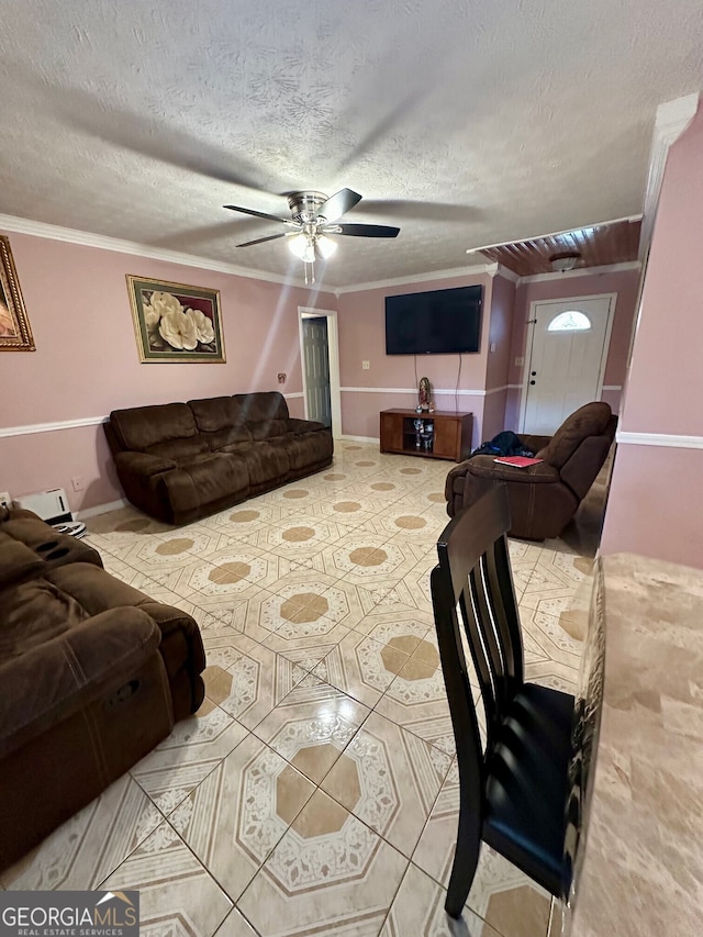 living room with tile patterned flooring, ceiling fan, ornamental molding, and a textured ceiling