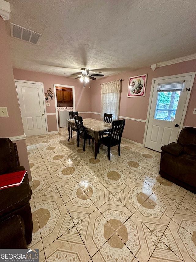 tiled dining room featuring ceiling fan, washer / dryer, and a textured ceiling