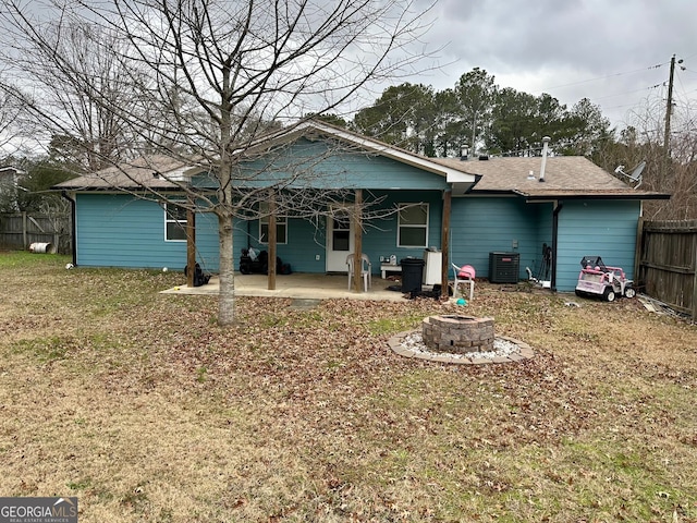 rear view of property with cooling unit, a patio area, a lawn, and an outdoor fire pit