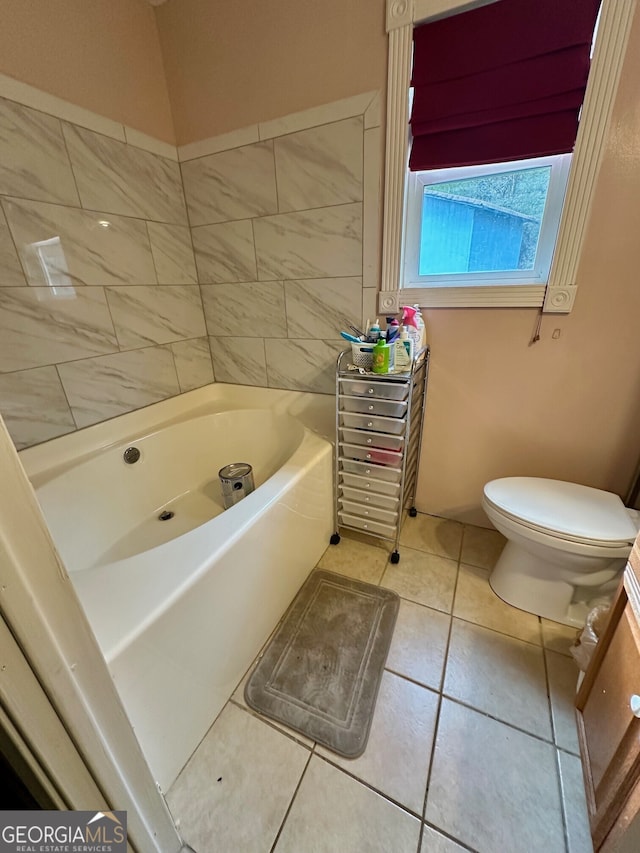 bathroom with tile patterned flooring, a tub, and toilet