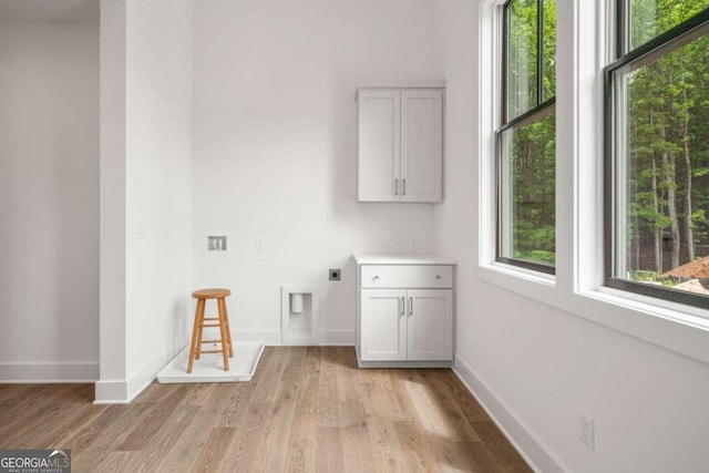 washroom with cabinets, plenty of natural light, hookup for an electric dryer, and light wood-type flooring