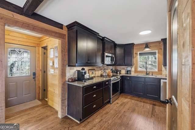 kitchen featuring light stone counters, sink, light wood-type flooring, and appliances with stainless steel finishes