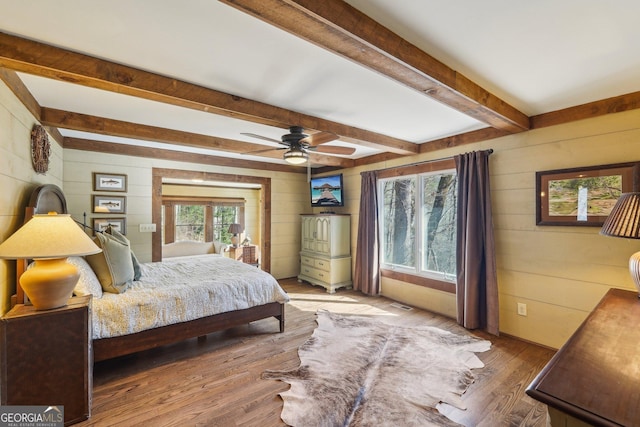 bedroom with hardwood / wood-style floors, ceiling fan, beamed ceiling, and wood walls