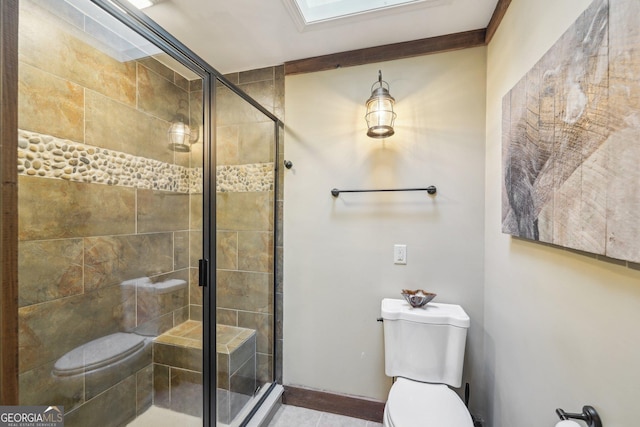 bathroom with a skylight, toilet, and a shower with shower door