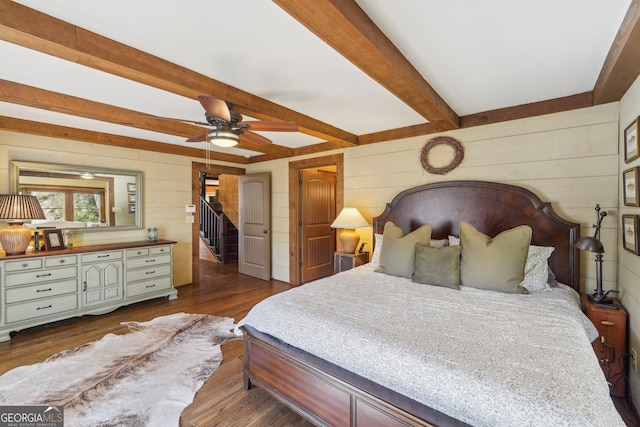 bedroom with dark hardwood / wood-style flooring, beam ceiling, ceiling fan, and wood walls