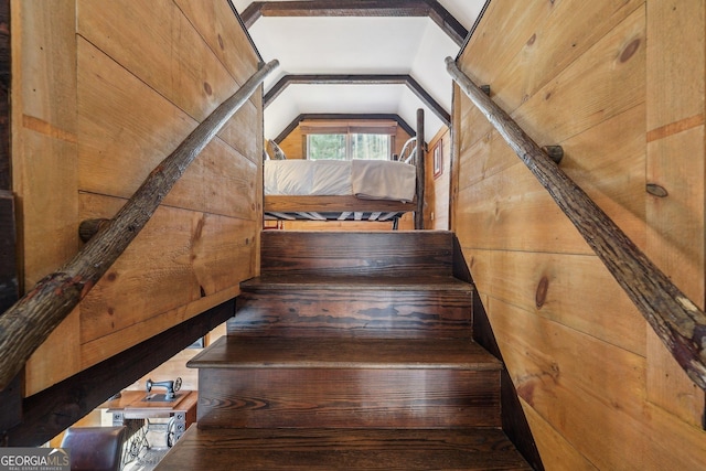 stairway featuring lofted ceiling and wood walls