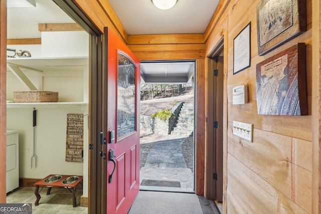 doorway to outside with washer / dryer and wooden walls