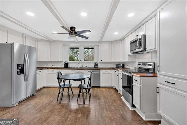 kitchen with stainless steel appliances, white cabinetry, wood-type flooring, and sink