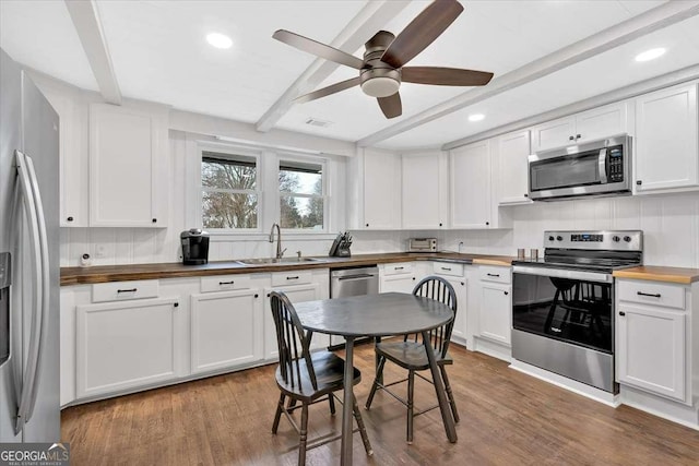 kitchen featuring stainless steel appliances, butcher block counters, sink, and white cabinets