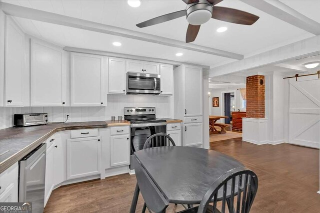 kitchen featuring white cabinetry, a barn door, and appliances with stainless steel finishes