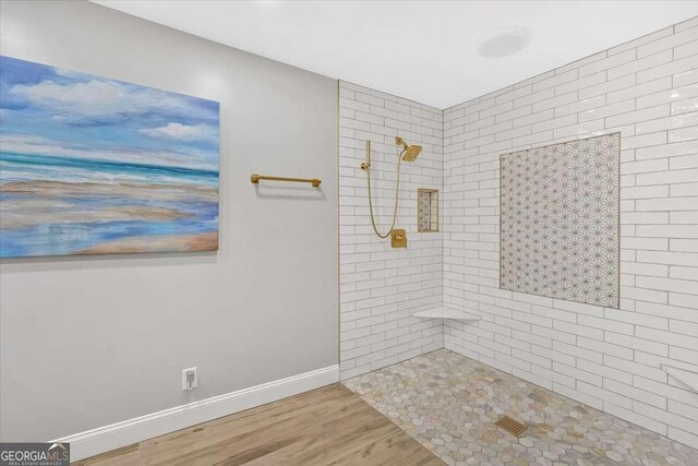 bathroom featuring hardwood / wood-style flooring and tiled shower