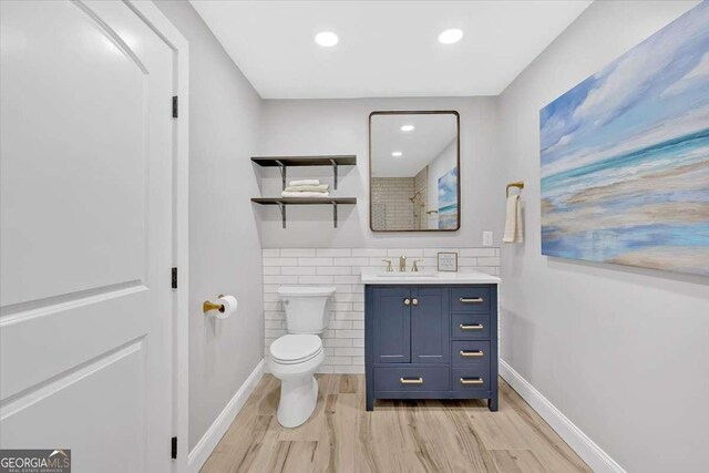 bathroom featuring wood-type flooring, tile walls, vanity, and toilet