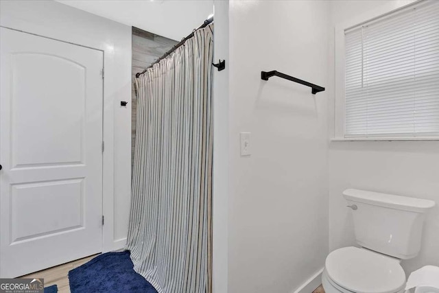 bathroom with walk in shower, toilet, and hardwood / wood-style floors