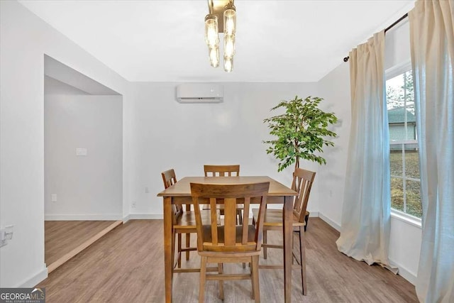 dining space featuring a wall mounted air conditioner and light wood-type flooring