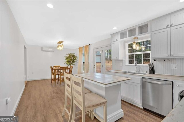 kitchen featuring pendant lighting, sink, stainless steel dishwasher, and white cabinets