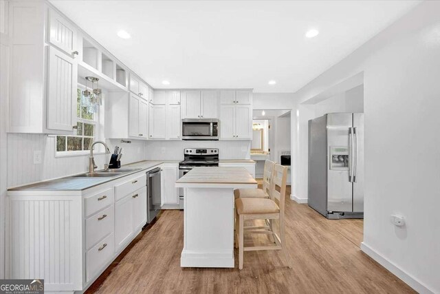 kitchen with white cabinetry, sink, stainless steel appliances, and a center island