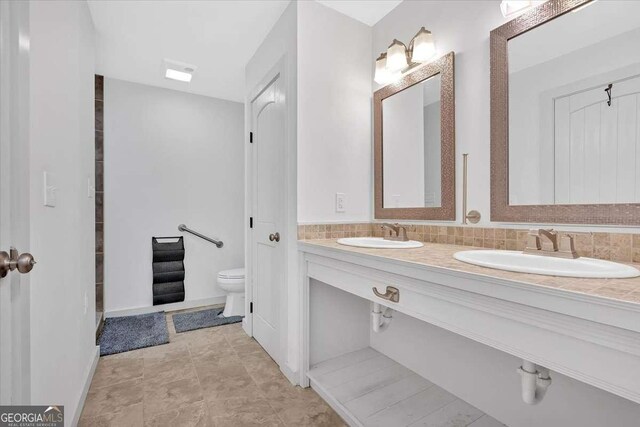 bathroom featuring vanity, backsplash, and toilet