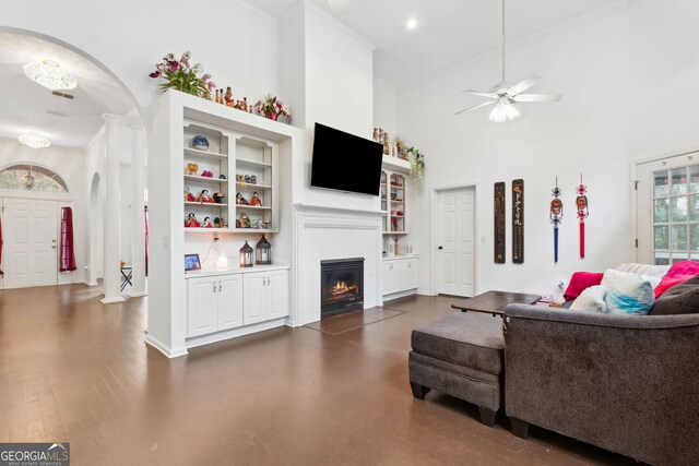 living room with crown molding, ceiling fan, decorative columns, dark hardwood / wood-style floors, and a high ceiling