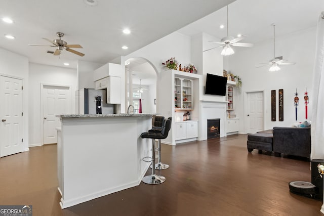 kitchen featuring stainless steel refrigerator, a breakfast bar, dark hardwood / wood-style floors, light stone counters, and white cabinets