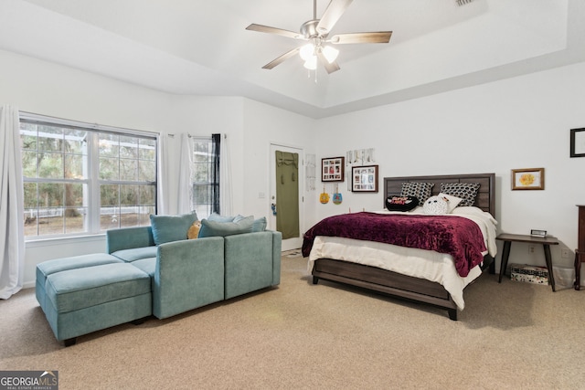 carpeted bedroom featuring a tray ceiling and ceiling fan