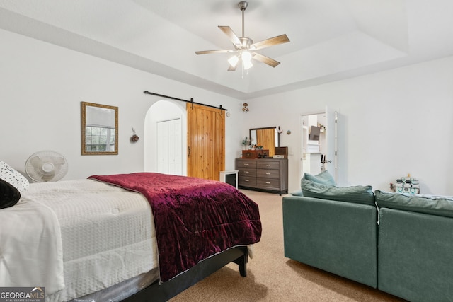 bedroom with a raised ceiling, a barn door, carpet floors, and ceiling fan