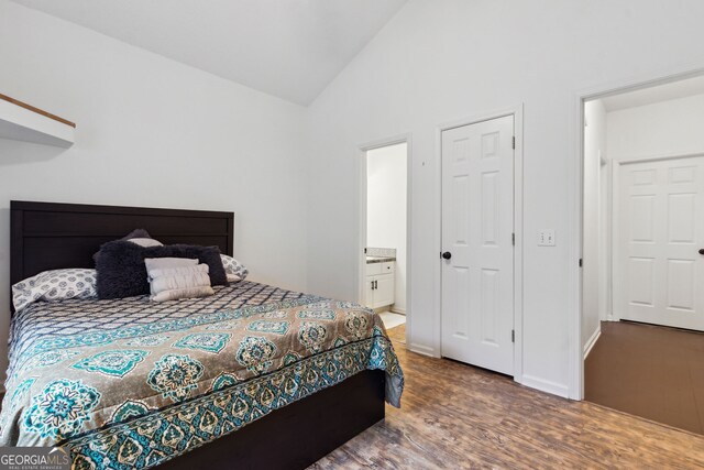 bedroom with wood-type flooring, ensuite bathroom, and vaulted ceiling