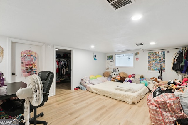 bedroom with a walk in closet, light hardwood / wood-style floors, and a closet