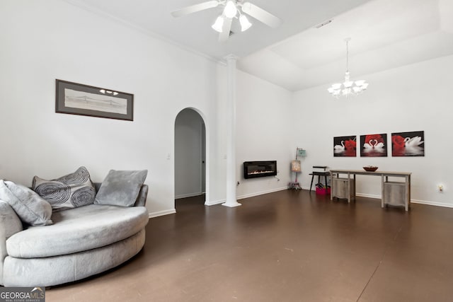 living room featuring ceiling fan with notable chandelier, a raised ceiling, and ornate columns