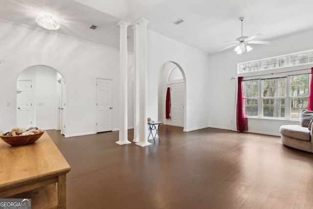 living room featuring ceiling fan, a towering ceiling, crown molding, and ornate columns