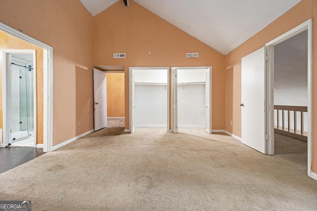 unfurnished bedroom featuring multiple closets, carpet floors, and high vaulted ceiling