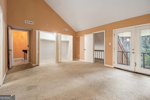 interior space with french doors, access to exterior, high vaulted ceiling, and light carpet