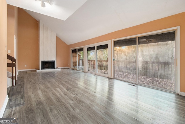 unfurnished living room featuring lofted ceiling, a large fireplace, and hardwood / wood-style floors