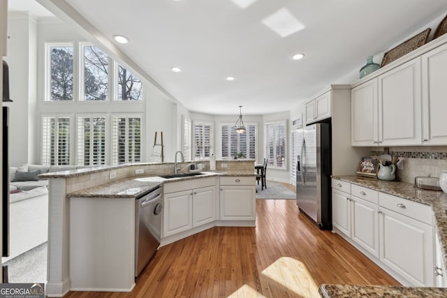 kitchen with white cabinetry, sink, decorative light fixtures, and stainless steel appliances