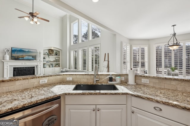 kitchen featuring white cabinetry, sink, stainless steel dishwasher, and light stone countertops