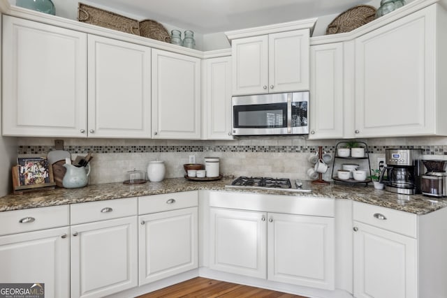 kitchen with tasteful backsplash, stainless steel appliances, and white cabinets