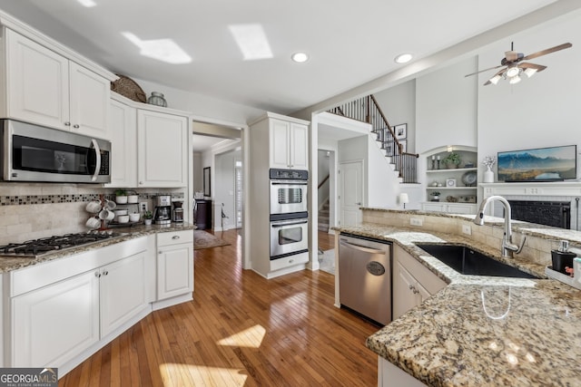 kitchen with light stone counters, stainless steel appliances, sink, and white cabinets