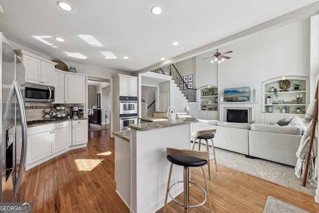 kitchen with white cabinetry, appliances with stainless steel finishes, a kitchen bar, and dark stone countertops