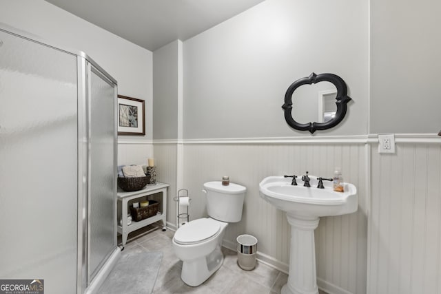 bathroom featuring a shower with door, sink, tile patterned floors, and toilet