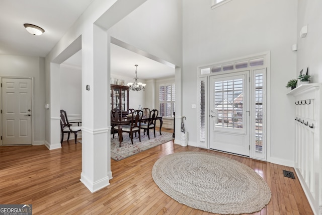 foyer featuring wood-type flooring, a towering ceiling, and a notable chandelier