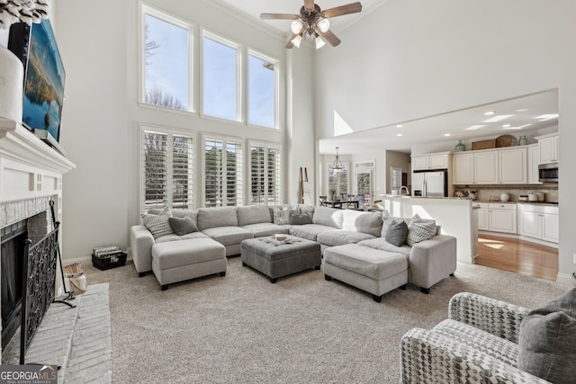 living room with ceiling fan, a healthy amount of sunlight, light hardwood / wood-style floors, and a brick fireplace