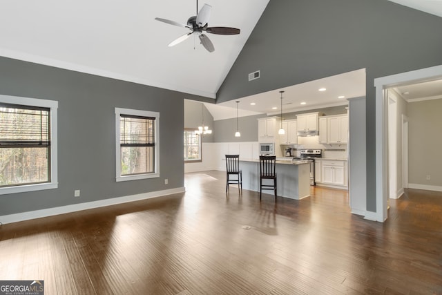 living room with dark hardwood / wood-style flooring, crown molding, ceiling fan with notable chandelier, and high vaulted ceiling