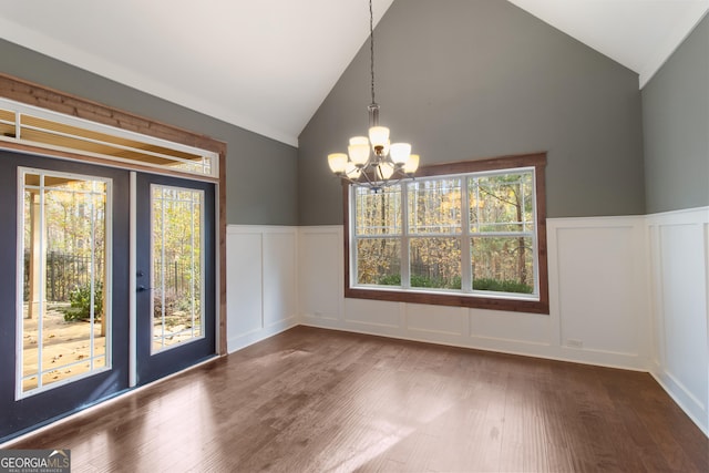 unfurnished dining area featuring an inviting chandelier, hardwood / wood-style flooring, lofted ceiling, and french doors