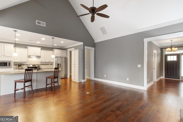 living room with dark hardwood / wood-style flooring, ceiling fan with notable chandelier, and high vaulted ceiling