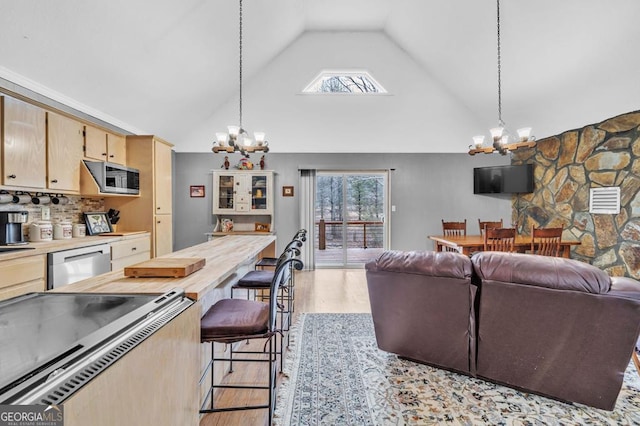 kitchen featuring stainless steel appliances, decorative light fixtures, an inviting chandelier, and light hardwood / wood-style flooring