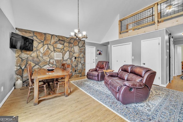 living room featuring an inviting chandelier, a fireplace, wood-type flooring, and high vaulted ceiling