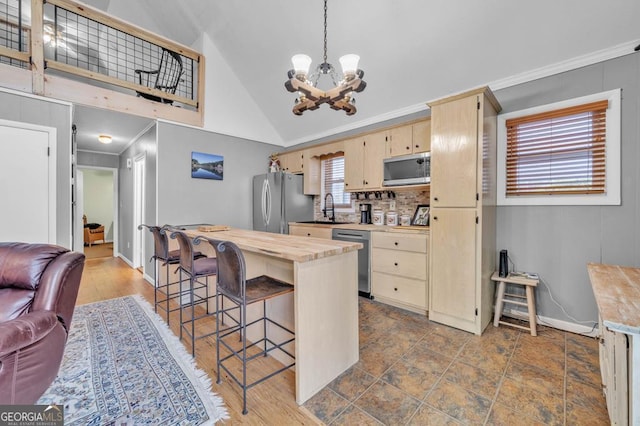 kitchen featuring wood counters, sink, a breakfast bar area, hanging light fixtures, and stainless steel appliances