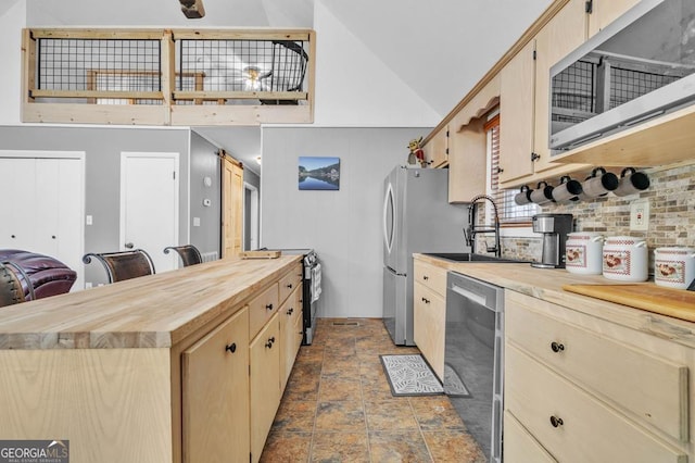 kitchen featuring appliances with stainless steel finishes, wood counters, lofted ceiling, decorative backsplash, and light brown cabinets